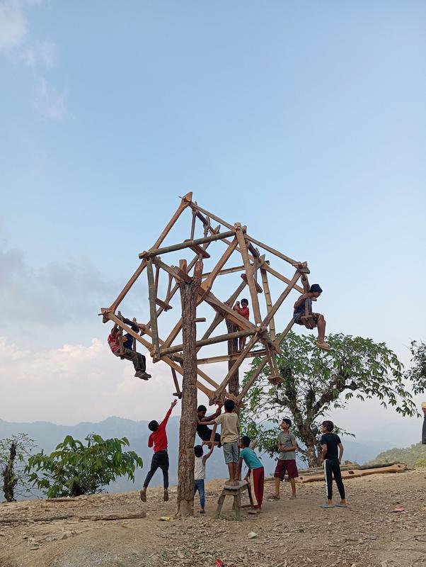 Children playing on a bamboo structure on a hilltop