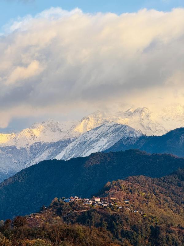 Snow-capped Himalayan range above a hillside village