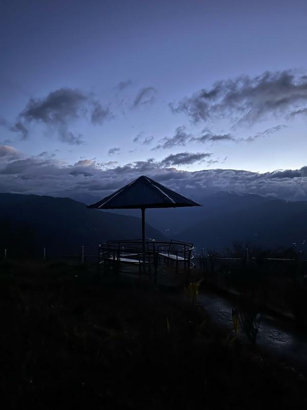 Silhouette of a gazebo at dusk overlooking misty hills